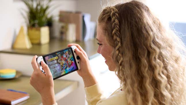 A blonde lady appears to be delighted by her Switch OLED model.