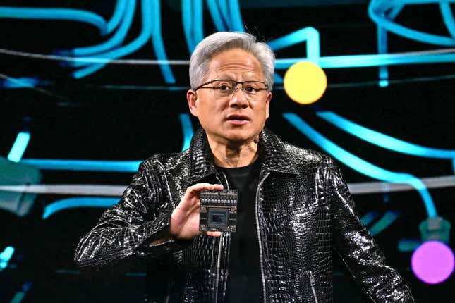 jensen huang wearing a black leather jacket while speaking and holding a chip in front of a display with neon blue lines and colorful lights